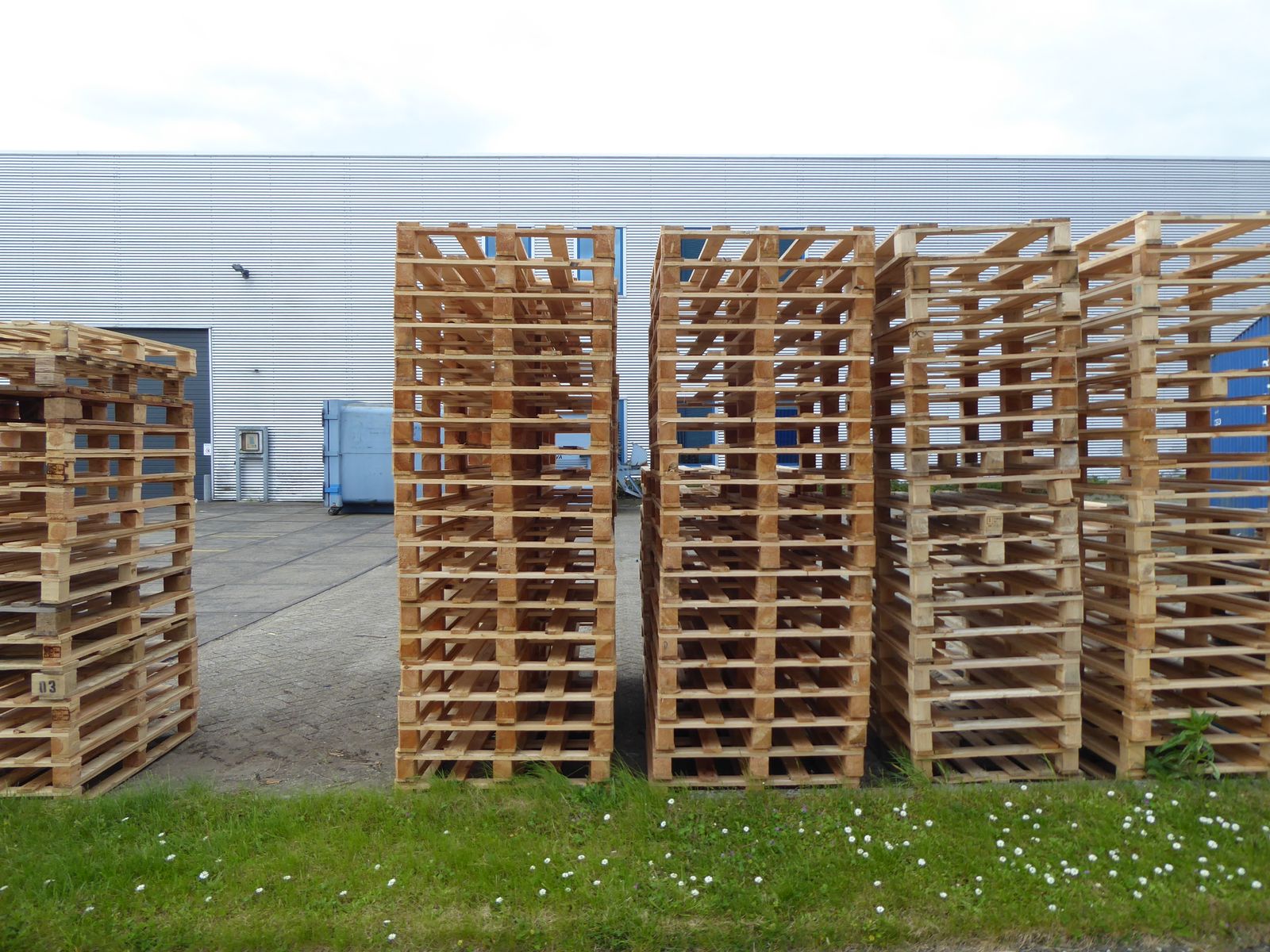 Stacked wooden pallets outside an industrial warehouse