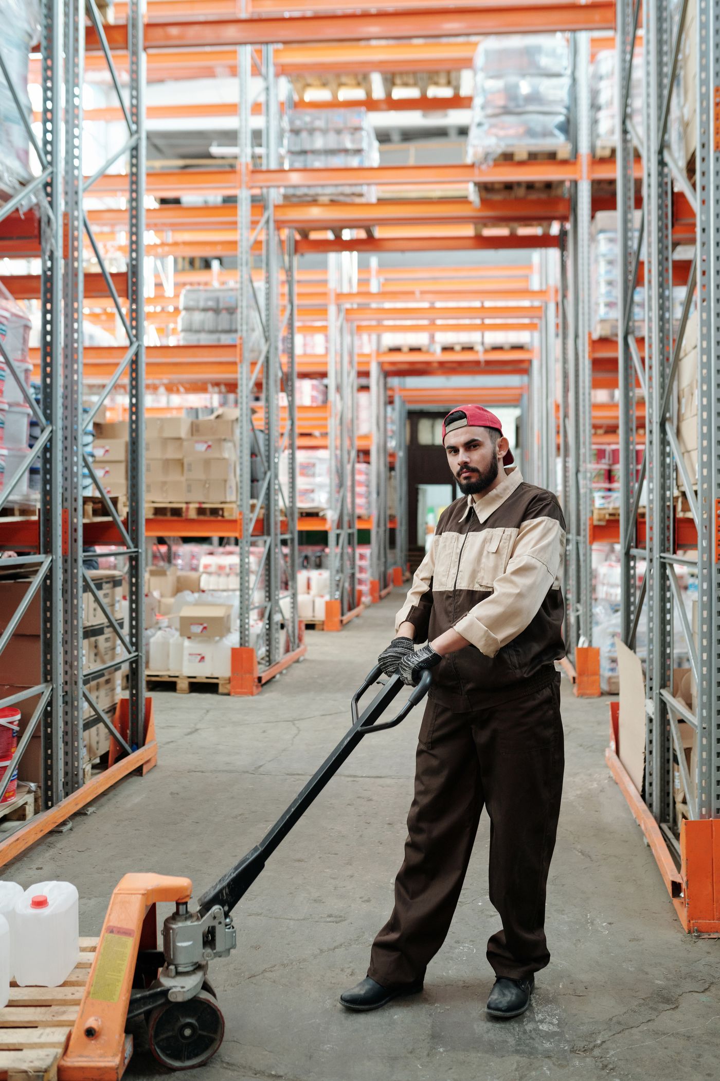 Worker with pallet jack in an organized retail stockroom